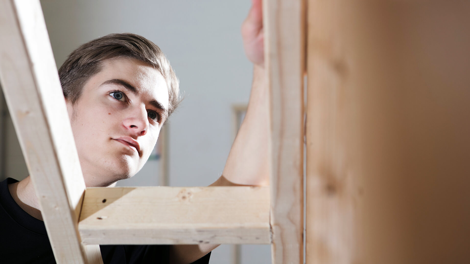 A young man inspecting his wood work.