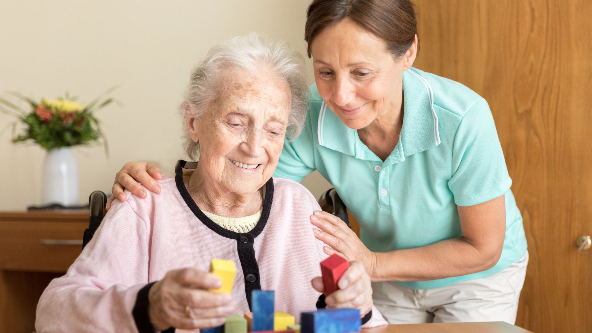 Nurse helping an older woman building blocks