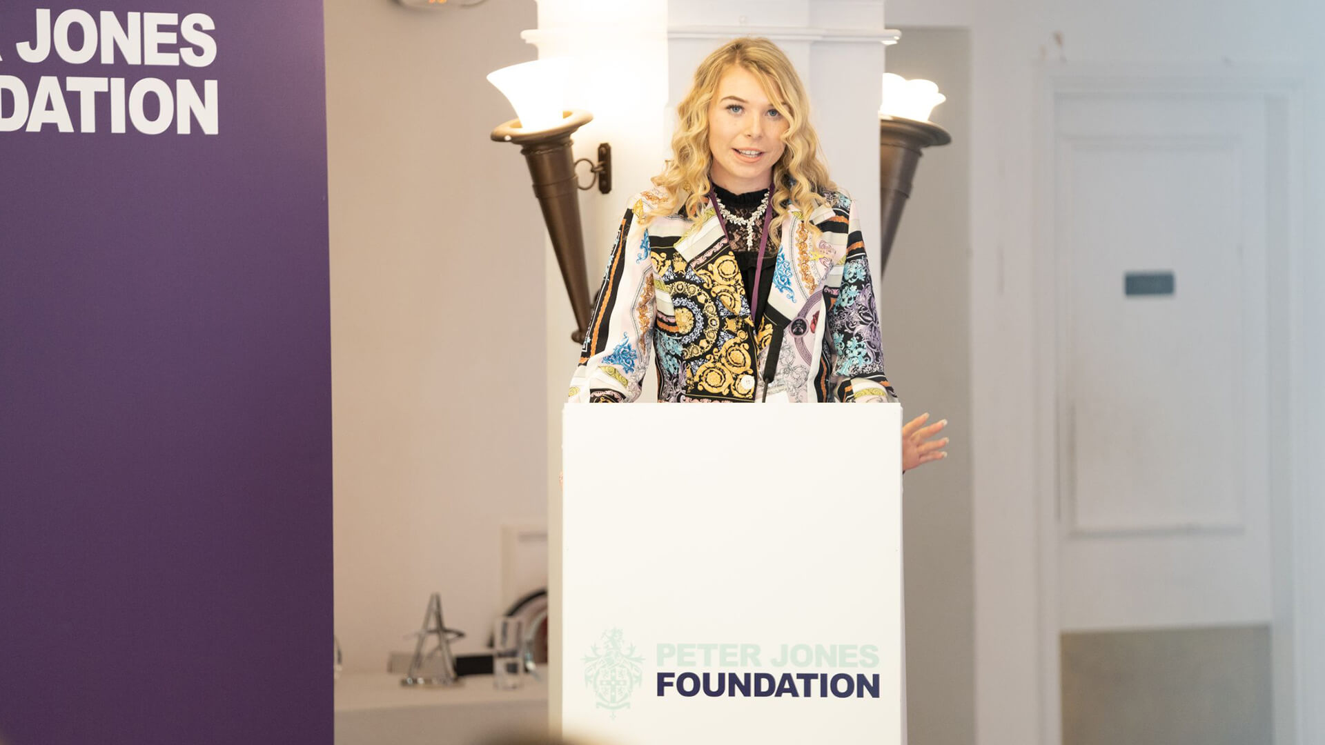 A young woman standing at a podium, giving a speech.