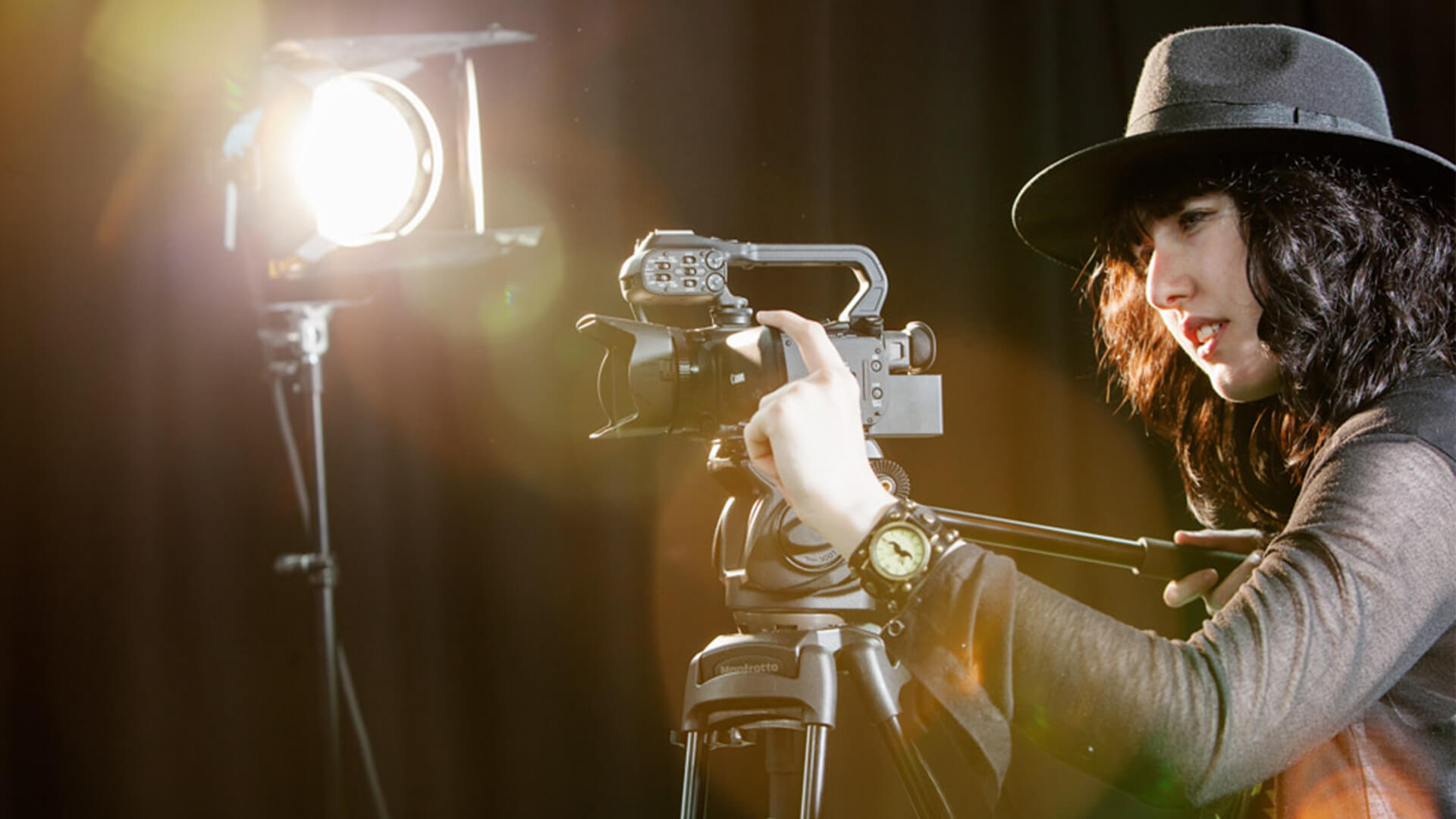 Young woman working with a camera on a stand.