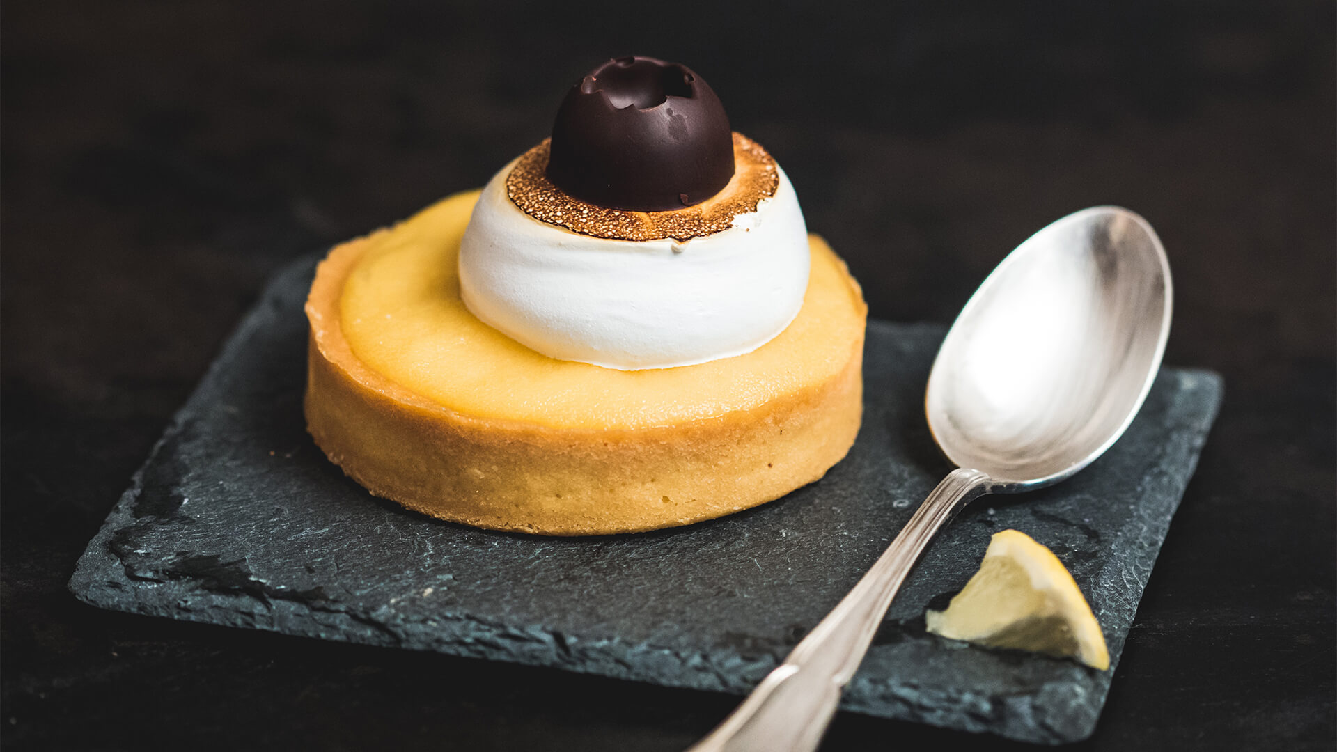 Lemon tart and spoon on a slate