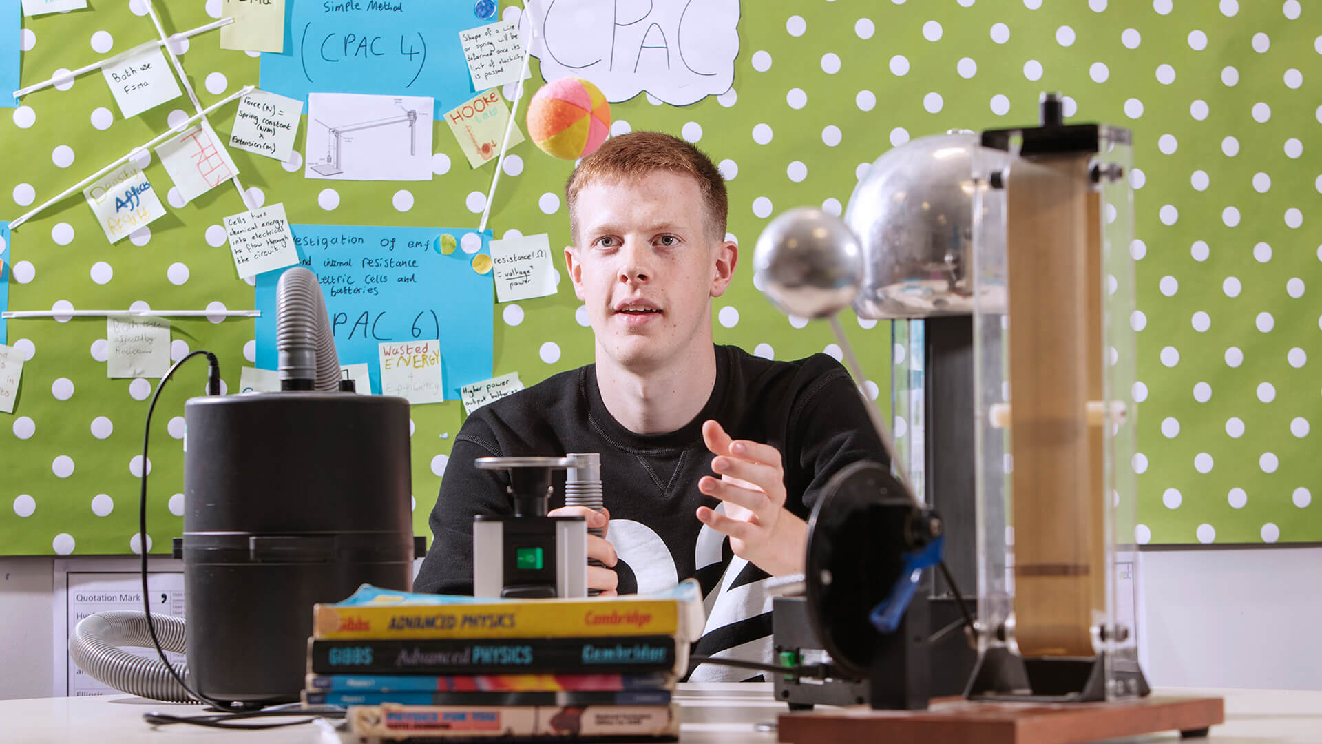 Young man doing a science experiment at a desk in a classroom.