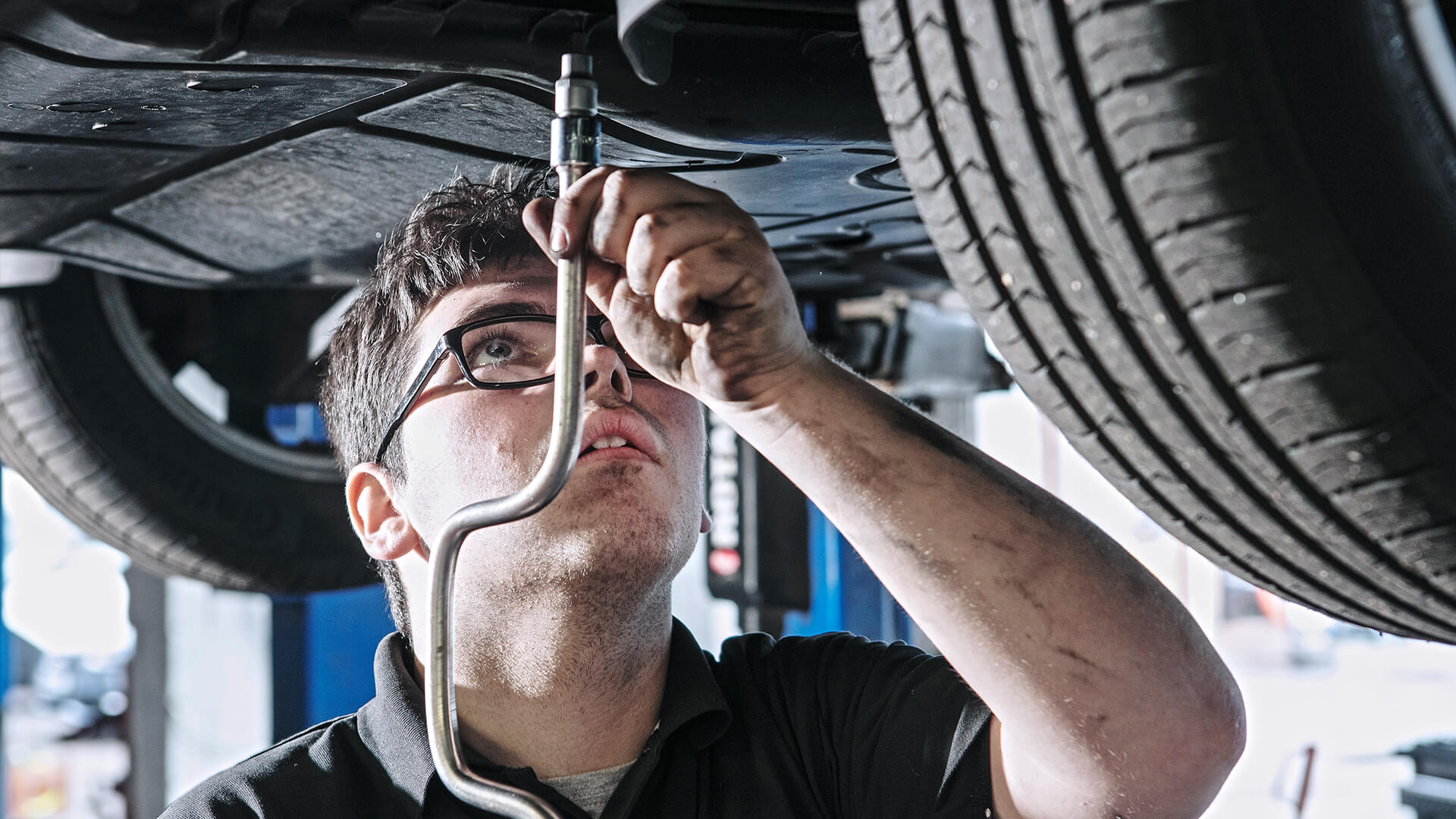 Young man working on the underneath of a car.