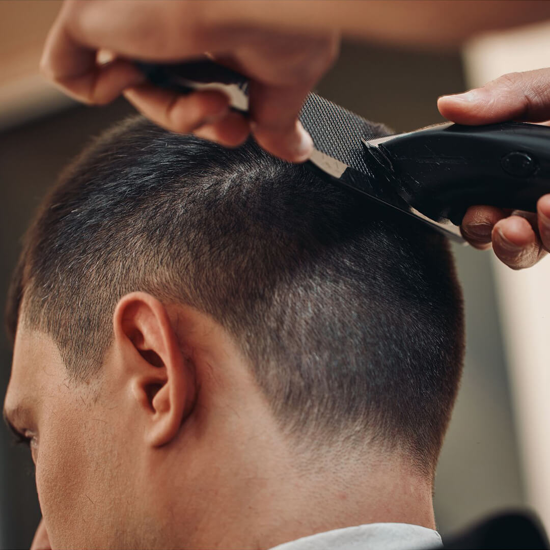 Barber cutting a mans hair. holding scissors and a comb.