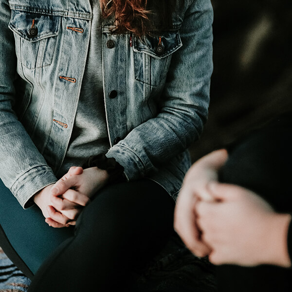 Two people sitting with their hands held together.