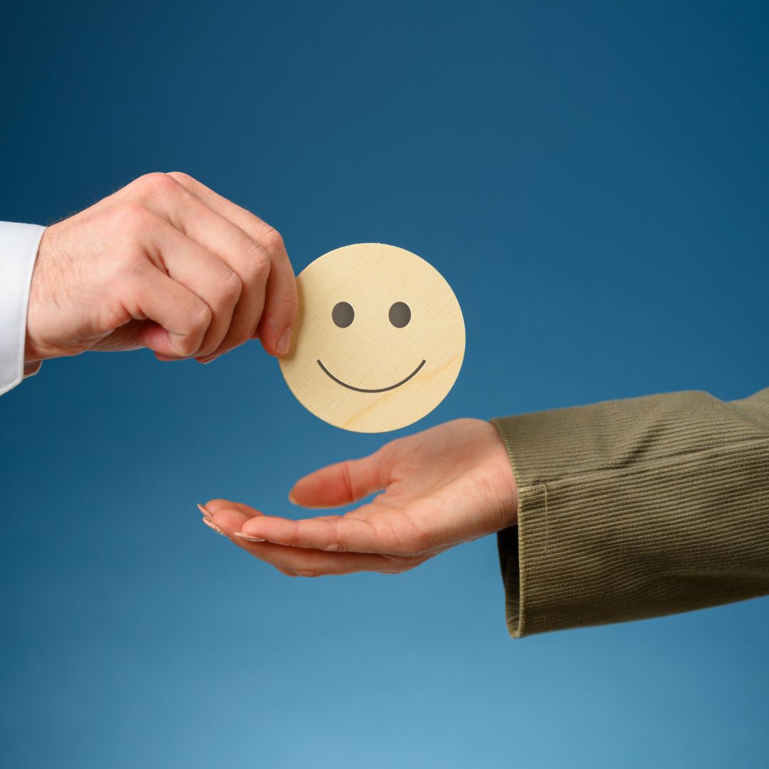 Person handing another person a wooden smiling face