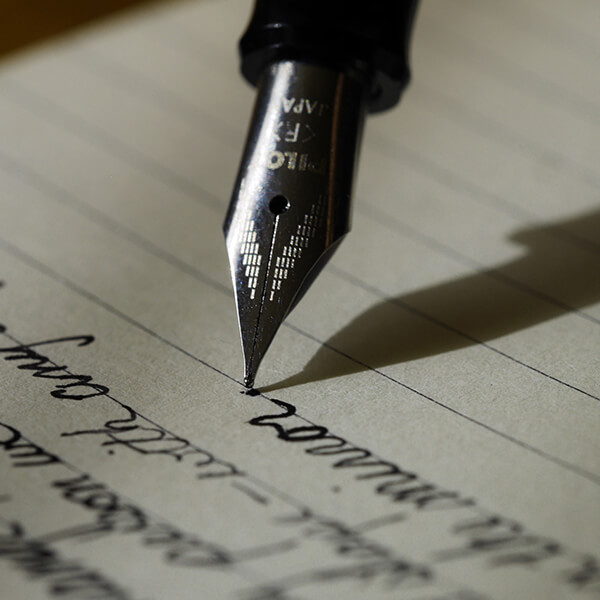 A fountain pen writing on lined paper.