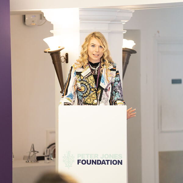 A young woman standing at a podium, giving a speech.