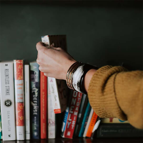 A row of books and a hand picking one out.