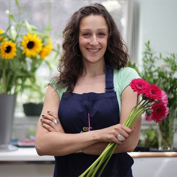 Young woman holding a bunch of pink flowers and smiling.