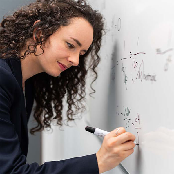 Teacher writing a sum on a whiteboard.