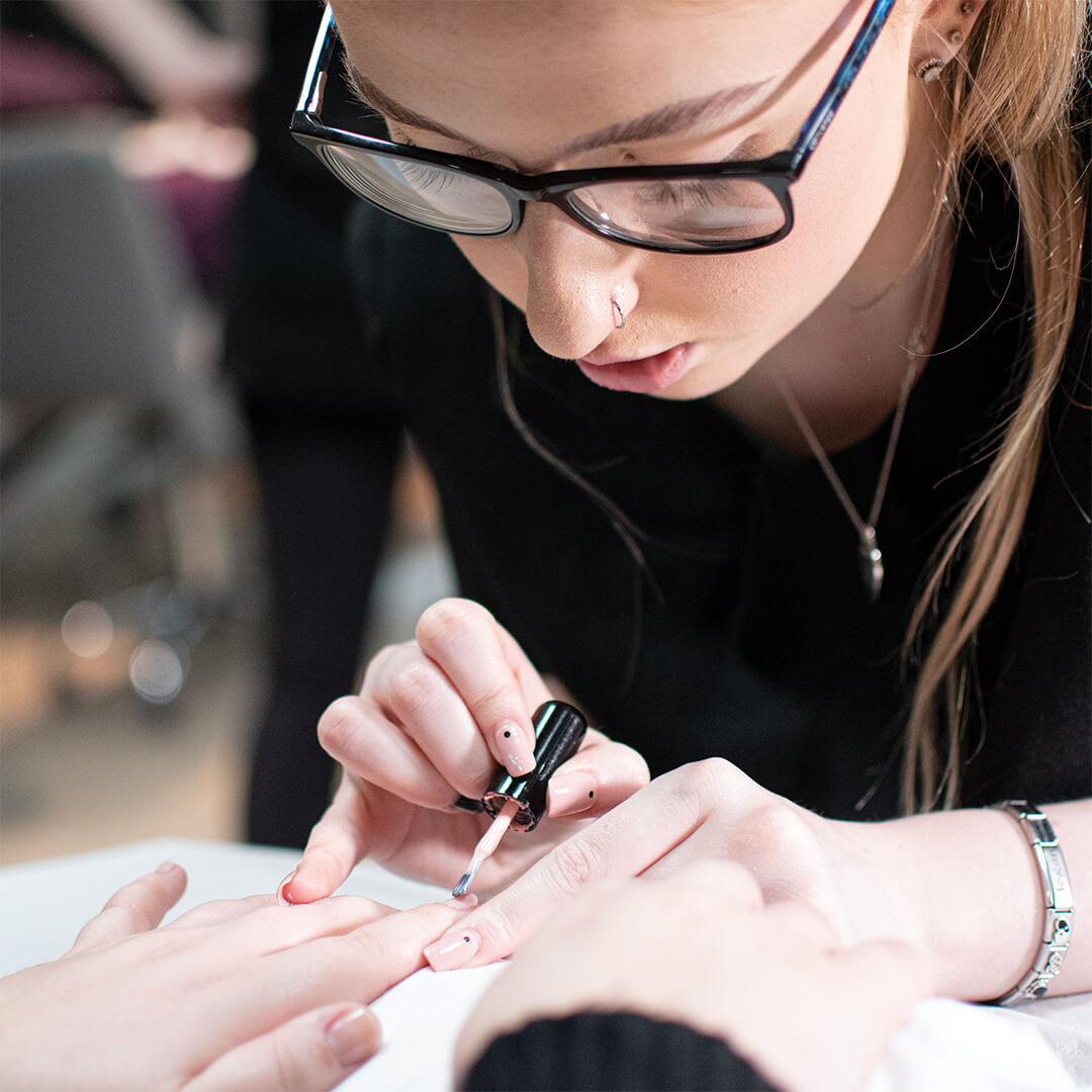 Young woman painting another persons nails.