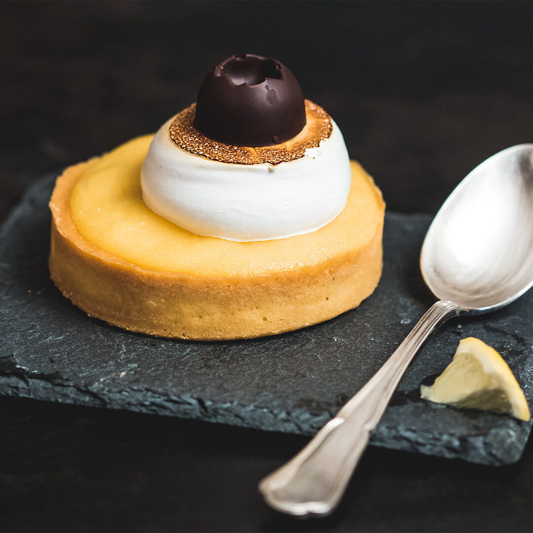 Lemon tart and spoon on a slate