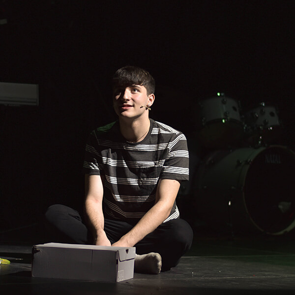 A young man sat on stage with a mic.