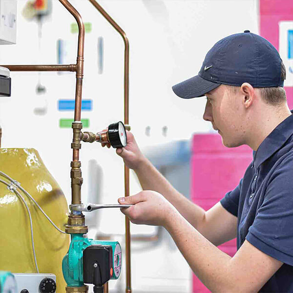 Young woman wearing a cap, working on pipes and checking the pressure.