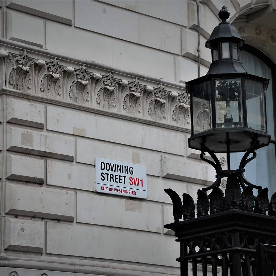 Downing Streets street sign on the wall of a building.