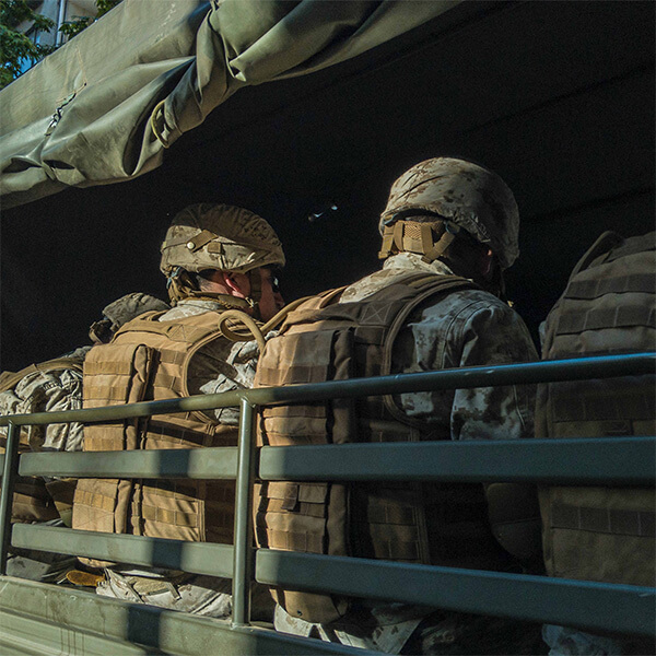 A bunch of army men in uniform, in an army vehicle.