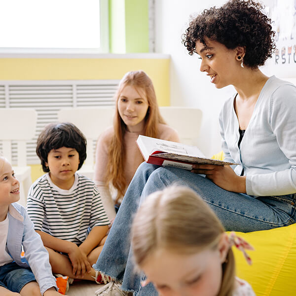 A young female teacher reading to four small children.