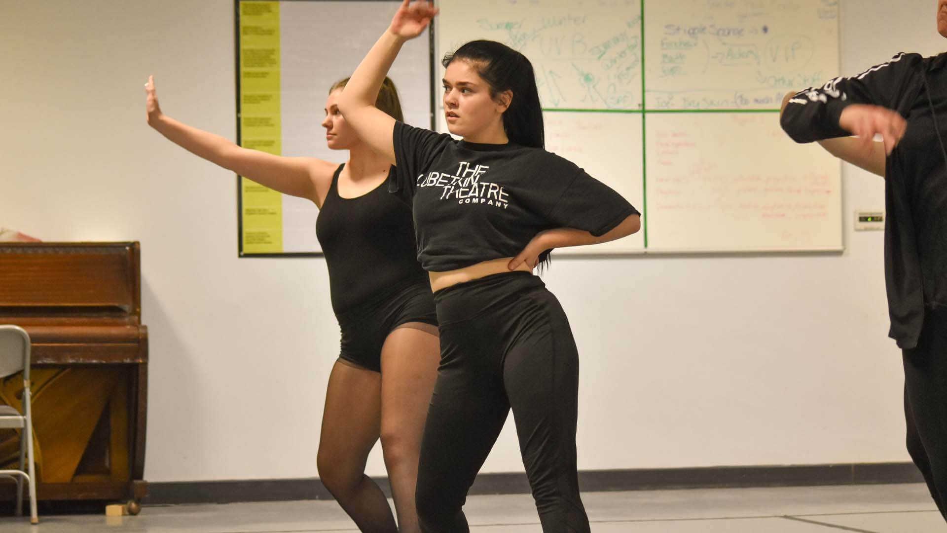 Three dance students, dressed in black, in a dance studio