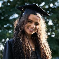 A young woman in mortar board smiles at the camera