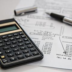 Close-up of a calculator resting on piece of paper with pens