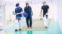 Three men dressed in cricket gear walking toward the camera