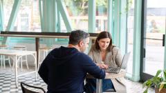 Two people sat with a laptop having a meeting in a café