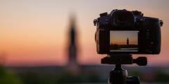 Close-up of a camera, on a stand, facing a sunset