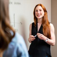 Teacher smiling and talking to student against to a whiteboard