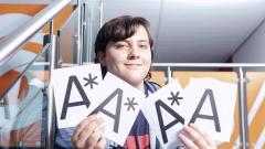 A student smiling at the camera holding 3 A stars and an A