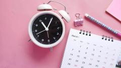 A calendar and clock on a pink table