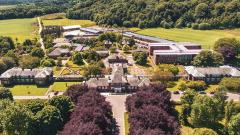 Aerial shot of the East Durham College Houghall Campus main campus building taken in June 2019, with fields and woodland in the background