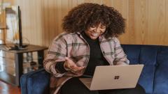 Lady sat on a sofa typing on a laptop