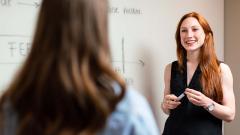 Teacher stood next to whiteboard holding a dry marker pen