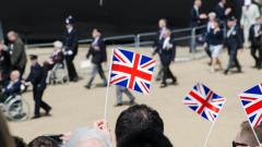 A crowd holding union jack flags with veterans in the background marching