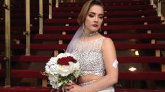 Student in bridal gown posing on stairs and holding a bouquet of flowers