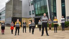 A group of EDC Progression coaches holding AOC Beacon Awards signs outside EDC peterlee campus