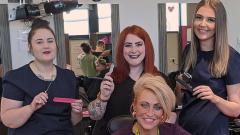 Three barbering students stood holding hairdressing equipment above Alison Scattergood's head