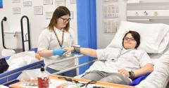 Two care students in the EDC mock hospital care room, one laid in a hospital bed