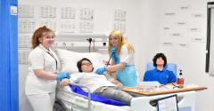 Three care students in the EDC mock hospital care room