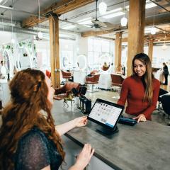 Two women with iPads smiling in a cafe