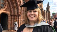 Emma Baker in graduation cap and gown, stood in front of an ornate building