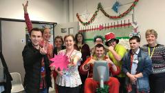 A group of 10 staff and foundation students smiling and gathered around exercise bike