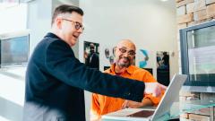 Two people having a work meeting, one pointing at a laptop screen