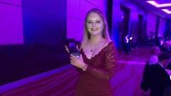 Kaylee McNally stood in a red dress holding trophy for best engineering apprentice