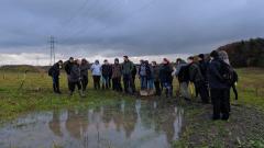 A large group of land and wildlife students in field observe large puddle