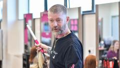 Lee Stafford holding curling tong and looking toward the camera