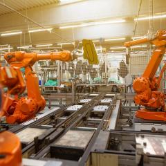 Orange robotic arms working in manufacturing environment