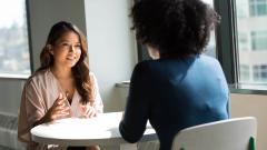 Two people having a meeting sat at a white table