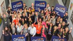 A large group of the Peterlee campus staff, taken from above, celebrating. Some are holding Ofsted GOOD signs